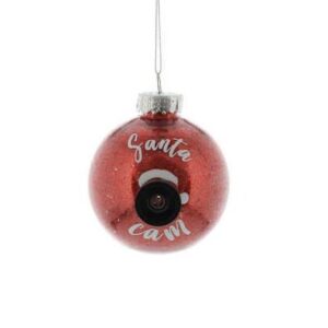 A round, clear Christmas tree bauble filled with red glitter on the inside and decorated on the outside with a black camera lens which has a red santa hat on top of it and white text around it that reads 'Santa Cam'. Hanging on a a silver string.