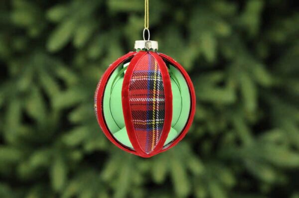 A metallic green, round shaped glass Christmas tree bauble with red tartan fabric segments and finished with red velour ribbon around the segments.