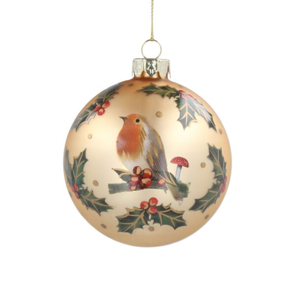 A matt gold glass Christmas tree bauble decorated witha a hand painted image of a Robin sitting on a branch next to a red and white toadstool and some holly with red berries. It is surrounded by sprigs of green holly leaves with red berries.