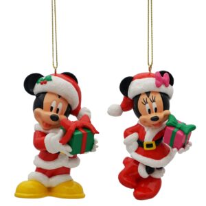 Disney mickey and minnie decorations. A polyresin Christmas tree decoration in the shape of Disney's Mickey Mouse. Mickey is wearing a red and white Santa suit with matching Santa hat and boots and is holding a green present wrapped up in a red ribbon and a polyresin Christmas tree decoration in the shape of Disney's Minnie Mouse. Minnie is wearing a red and white Santa dress with matching Santa hat and boots and is holding a pink present wrapped up in a green ribbon.