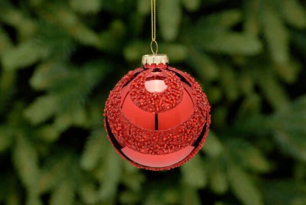 A metallic red, glass Christmas tree bauble decorated with alternating swags of tiny red beads all over. Hanging from a gold string.