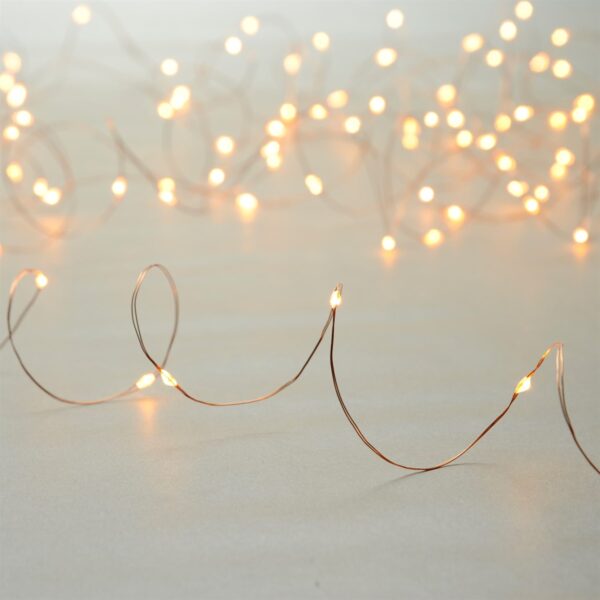 An illuminated set of 100 Amber Battery Operated Dewdrop Lights on a copper wire.