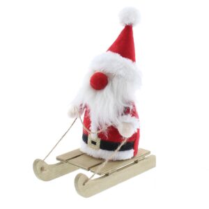 A plush Santa Claus figurine with a red fabric suit and matching hat, white fluffy beard and red nose sitting upon a wooden sleigh.