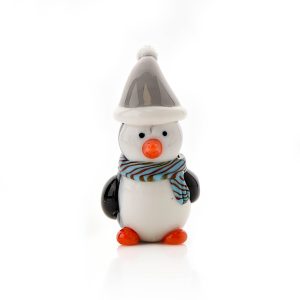 Image shows a 4 cm tall hand blown glass penguin figurine. His body and head are made from white glass, his wings and eyes are black and his beak and feet are bright orange. He wears a grey and white stripy scarf and matching Santa hat. Shown against a white background.