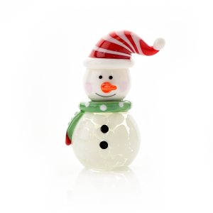 A hand finished blown glass ornament of a snowman. He has a round body of white glass white two dots of black for buttons. His round head has two black dots of 'coal' for eyes and a bright orange carrot nose and a lovely wide smile. He is wearing an adorable red and white stripey santa hat and green polka dot scarf. Shown on a white background.