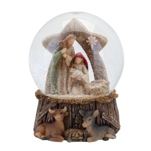 A large nativity snowglobe. The base of this snowglobe features a cow and a donkey lying in straw against a wooden wall topped with straw. Above, inside the globe, Mary and Joseph cradle the baby Jesus beneath a star shaped archway looking over the manger.