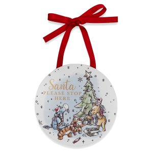 Disney Winnie Hanging Plaque featuring a colourful drawing of Pooh, Piglet, Tigger and Eyeore decorating a Christmas tree. It has gold text that reads "Santa Please Stop Here" and hangs from a red ribbon.