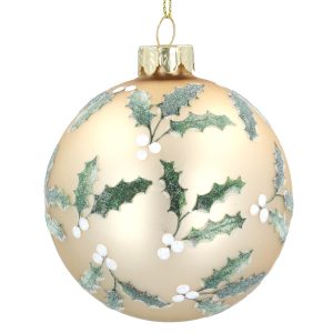 An 8cm glass Christmas bauble by Gisela Graham. This pale gold bauble has a repeating design of dark green holly leaves with white berry clusters all over it. It is shown on a white background.