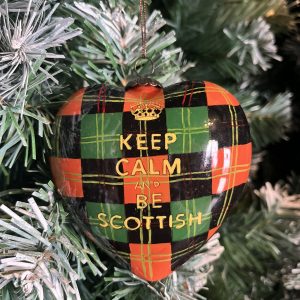 This hand painted Heart shaped glass Christmas bauble features a background of red and green tartan with the words "Keep Calm and be Scottish" on the front in gold beneath a gold crown. A twist on the iconic Ministry of Information posters of wartime Britain.These baubles bring a lovely touch of Scotland to your Christmas Tree or a thoughtful gift for a far-from-home Scot!