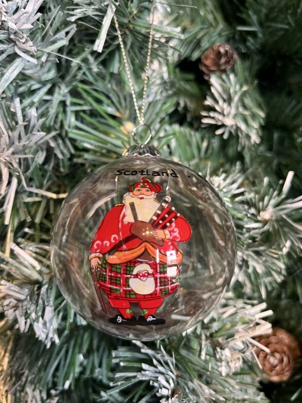 This hand painted round, clear glass Christmas bauble features a jolly Scottish Piping Santa on both sides. He is dressed in traditional Highland Regalia, complete with kilt and sporran! Scribed with the word 'Scotland' three times around the neck this baubles bring a lovely touch of Scotland to your Christmas Tree or a thoughtful gift for a far-from-home Scot!