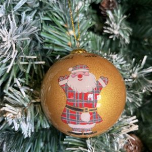 A gold glass Christmas tree bauble decorated with a hand painted Cheerful Tartan Clad Santa Claus wearing a kilt and sporran hanging on a Christmas tree.