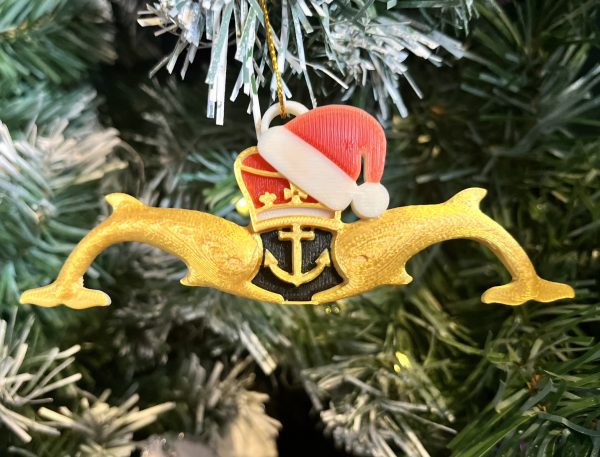 3D Printed Gold Submariners Dolphins with Santa Hat Tree Decoration Made locally, these 3D Printed Gold Submariners Dolphins Tree Decorations are the perfect Christmas gift for  the Submariner or sailor in your life. The measure 12cm x 4cm and feature red, white and black detail behind the crown and anchor with a red and white Santa hat ahnging off the crown at a jaunty angle. Supplied on a gold string ready for hanging on the tree.