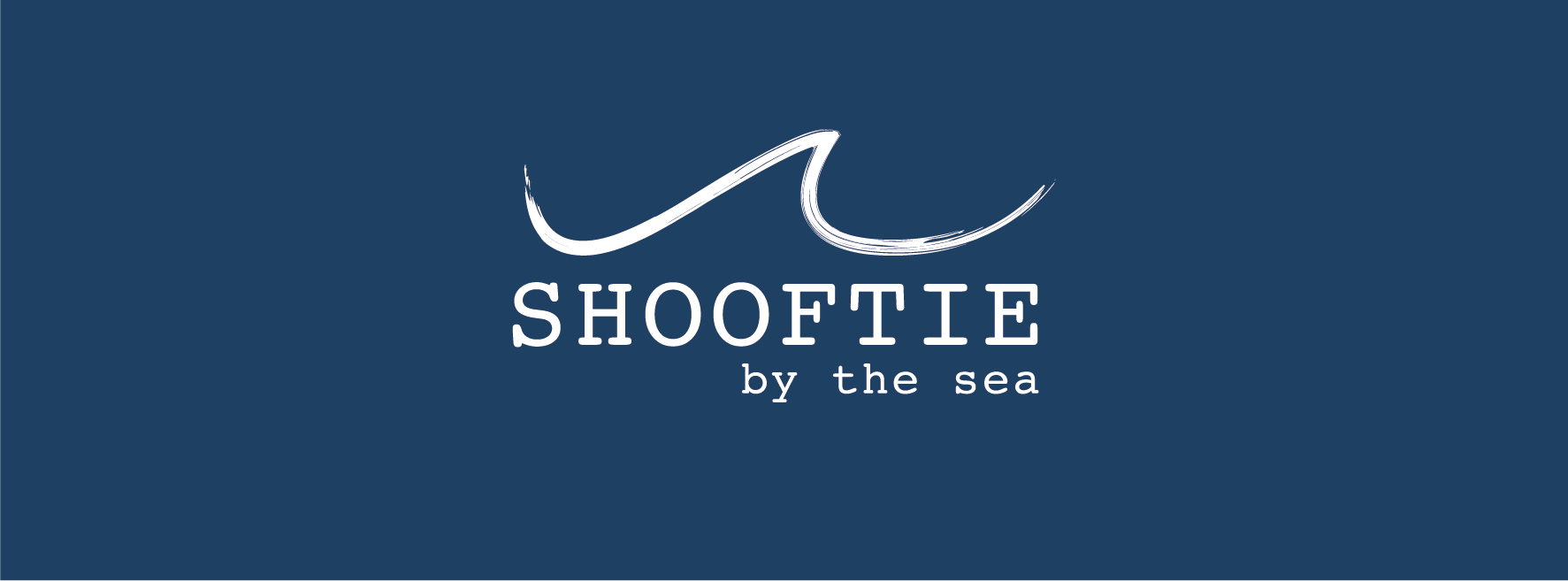 Logo featuring a stylized wave above the text "SHOOFTIE by the sea" on a dark blue background.