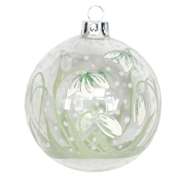 Clear glass ornament featuring white snow drop floral patterns green delicate green leaves , and painted snow fall with silver glitter accents