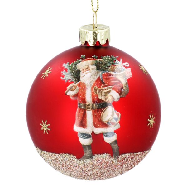 A decorative red Christmas ornament features a traditiomal looking Santa Claus with a sack of gifts over his shoilder and holding a drum, embellished with gold glitter snowflakes with a gold glitter base.