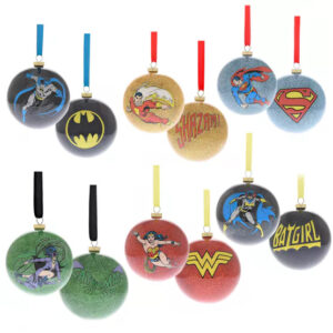 A set of six sparkly DC Comic superhero Christmas baubles featuring various symbols and characters, including Batman, Superman, Shazam, Wonder Woman, Batgirl, and Swamp Thing, with colored ribbons for hanging.